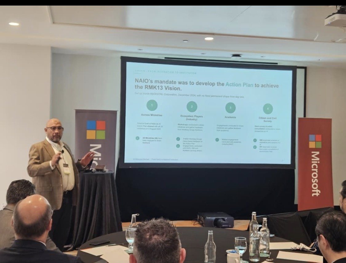 Reza Ali presenting at the Malaysia Public Sector Executive Roundtable hosted by Microsoft, speaking from a lectern beside a screen, in a room of seated guests.
