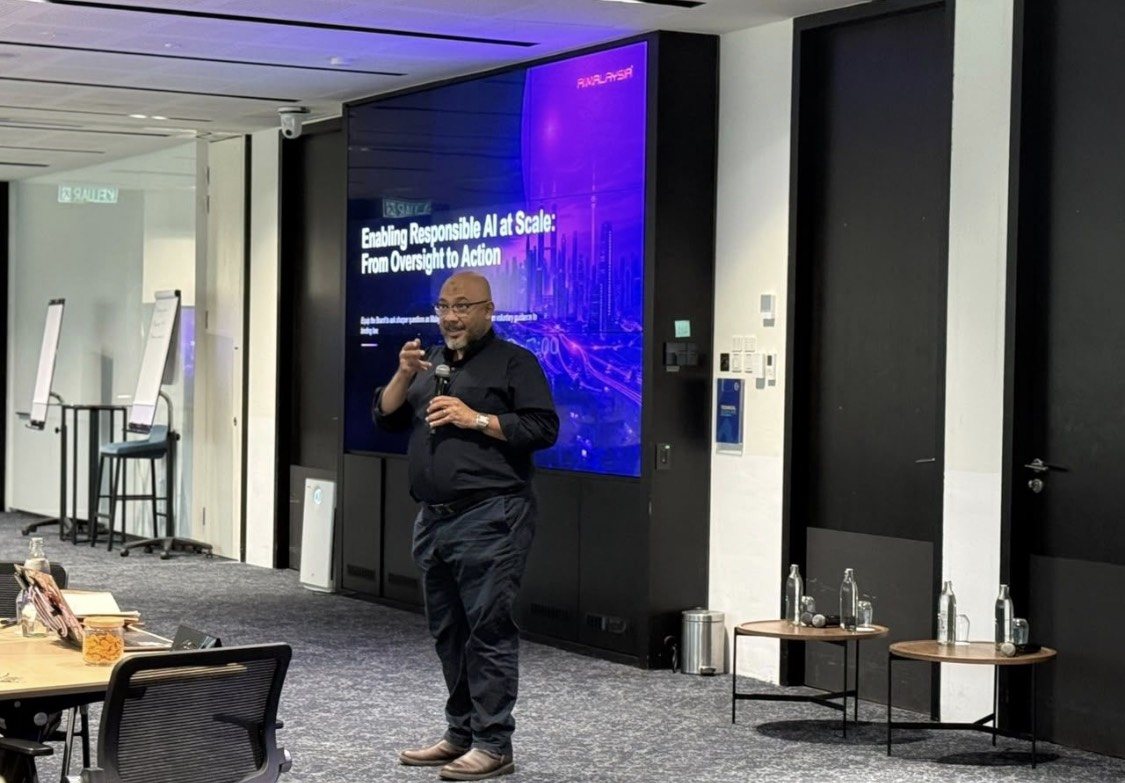 Reza Ali speaking with a microphone at the PETRONAS Board Excellence Programme in Bangi. Behind him a screen shows his session title, Enabling Responsible AI at Scale: From Oversight to Action.